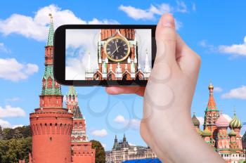 travel concept - tourist photographs picture of clock on Spasskaya tower of Moscow Kremlin on smartphone