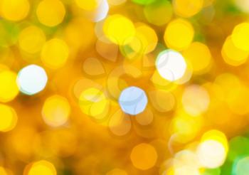 abstract blurred background - yellow and green twinkling Christmas lights bokeh of electric garlands on Xmas tree