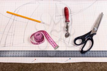dressmaking still life - top view of cutting table with tissue, pencil, pattern, tailoring tools