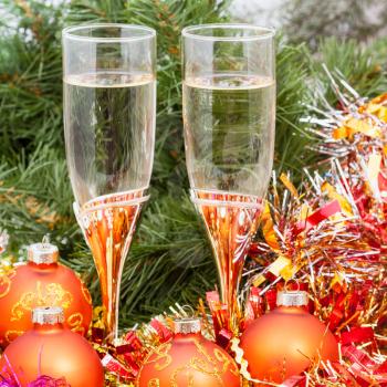 Christmas still life - golden Xmas balls and tinsel and two glasses of champagne on Christmas tree background