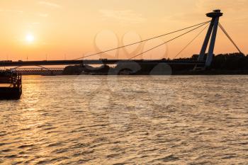 travel to Bratislava city - view of SNP bridge across Danube river at yellow dawn