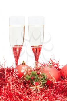 two glasses of sparkling wine and angel figure at red Christmas decorations isolated on white background