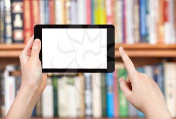 hand holds tablet pc with cut out screen and book shelves on background