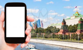 travel concept - hand holds smartphone with cut out screen and Moscow city on background