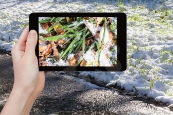 season concept - man taking picture of first snow at lawn on tablet pc