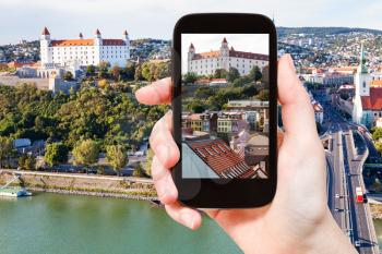 travel concept - tourist snapshot of Bratislava Hrad castle over old town on smartphone