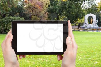 travel concept - tourist photographs green lawn and Johann Strauss in Stadtpark (City Park) in Vienna on tablet pc with cut out screen with blank place for advertising logo