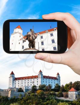 travel concept - tourist snapshot of statue of King Svatopluk I in Bratislava Hrad castle on smartphone