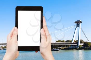 travel concept - tourist photographs of SNP Bridge (UFO bridge, Novy Most, New Bridge) over Danube river in Bratislava on tablet pc with cut out screen with blank place for advertising logo