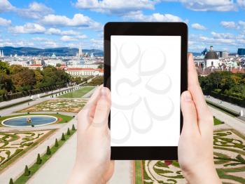 travel concept - tourist photographs lawns of Belvedere Palace in Vienna on tablet pc with cut out screen with blank place for advertising logo