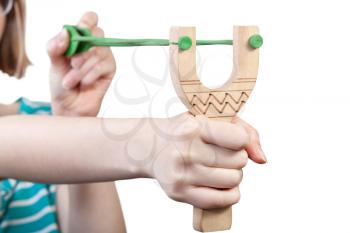 girl pulls green rubber band of simple wooden slingshot isolated on white background
