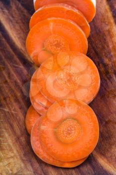 sliced fresh carrot on wooden cutting board close up