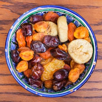top view of Central Asian dried fruits in traditional ceramic bowl on wooden table