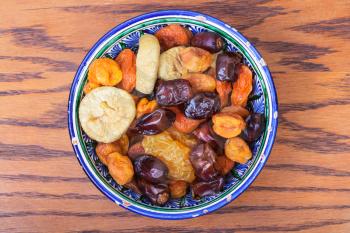 above view of Central Asian dried fruits in traditional ceramic bowl on wooden table