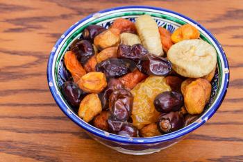 Central Asian dried fruits in traditional ceramic bowl on wooden table