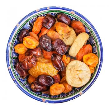 top view of Central Asian dried fruits in traditional ceramic bowl isolated on white background
