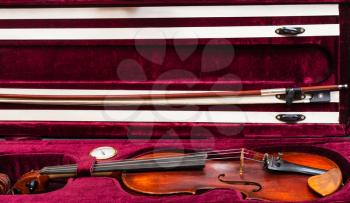 old wooden violin with bow in red velvet case