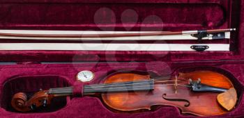 old wooden fiddle with bow in red velvet case
