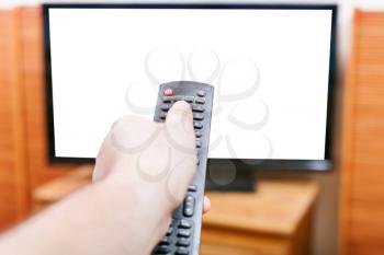 Hand turns on TV with cut out screen by remote control in living room