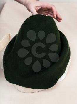 workshop for alpine felt hat making - hatter fixes a felt hood on wooden hat-block for shaping