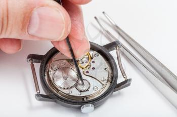 adjusting old mechanic wristwatch - horologer repairs old watch close up