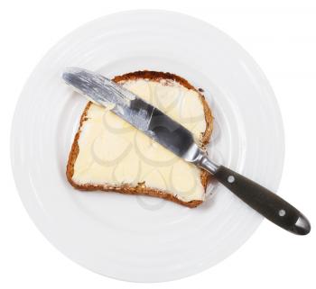 above view of table knife on grain bread and butter sandwich on white plate isolated on white background