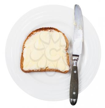top view of grain bread and butter sandwich with table knife on white plate isolated on white background