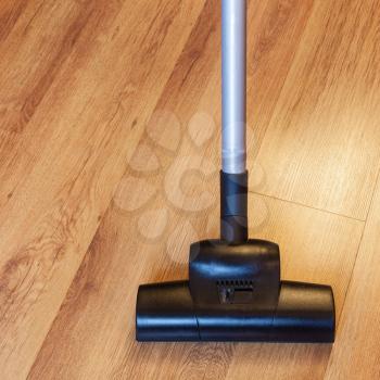 front view of clearing of laminate floor by vacuum cleaner at home