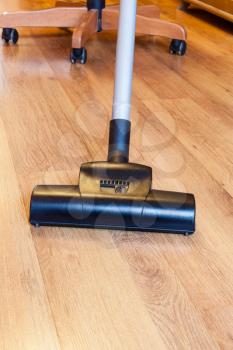 front view of cleaning of parquet floor by vacuum cleaner at home