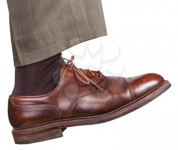 side view of male right leg in brown shoe takes a step isolated on white background