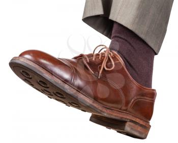 male left foot in brown shoe takes a step isolated on white background