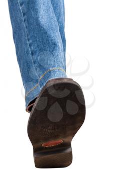 direct view of male left leg in jeans and brown shoe takes a step isolated on white background