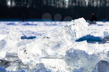 ice blocks illuminated by sun on surface of frozen lake in cold winter day