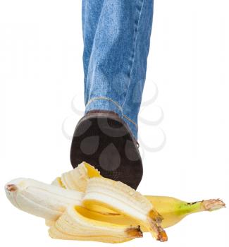 male left foot in jeans and brown shoe stepping on banana isolated on white background