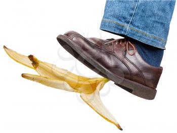 male left leg in jeans and brown shoe slips on a banana peel isolated on white background