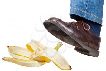 male left foot in jeans and brown shoe slips on a banana peel isolated on white background