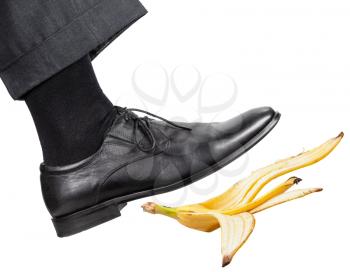 male leg in the right black shoe slips on a banana peel isolated on white background