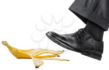 male foot in the left black shoe slips on a banana peel isolated on white background