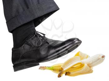 male foot in the right black shoe slips on a banana peel isolated on white background