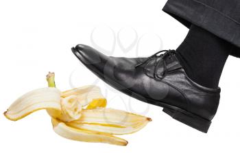 male leg in the left black shoe slips on a banana peel isolated on white background
