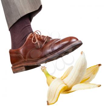 male foot in the right brown shoe slips on a banana peel isolated on white background