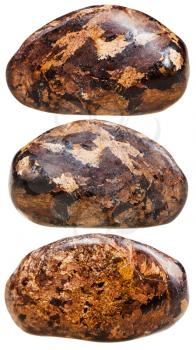macro shooting of natural mineral stone - three tumbled Bronzite gemstones isolated on white background