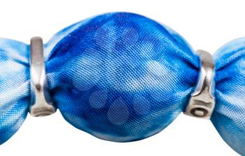 detail of handmade textile necklace - blue painted silk batik bead and silver rings close up isolated on white background
