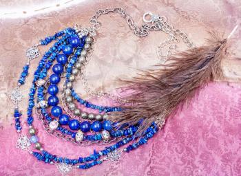 blue necklace from natural gemstones (lapis lazuli, pyrite , lazurite, glass lampwork beads) on painted textile background