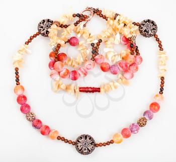 pink and yellow necklace from natural gemstones (pink Agate Dragon veins, horn, shell, mahogany obsidian beads and carved copper balls) on white background
