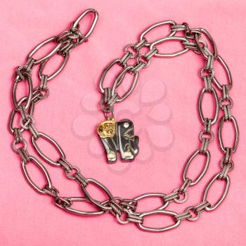 top view of pendant from black chain and elephant figure from carved hematite on pink textile background