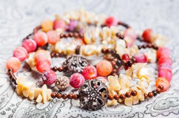 tangled pink and yellow necklace from natural gemstones (pink Agate Dragon veins, horn, shell, mahogany obsidian beads and carved copper balls) on textile background
