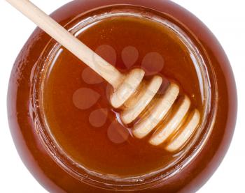 top view of wooden stick on glass jar with brown honey isolated on white background