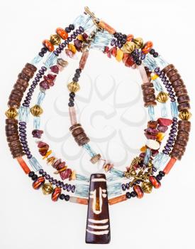 african style necklace from natural chipping gemstones (mookaite, jasper), carved bone and coconut, glass beads, brass balls on white background