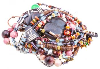 pile of matted necklaces from natural gemstones and carved bone and coconut beads on white textile background